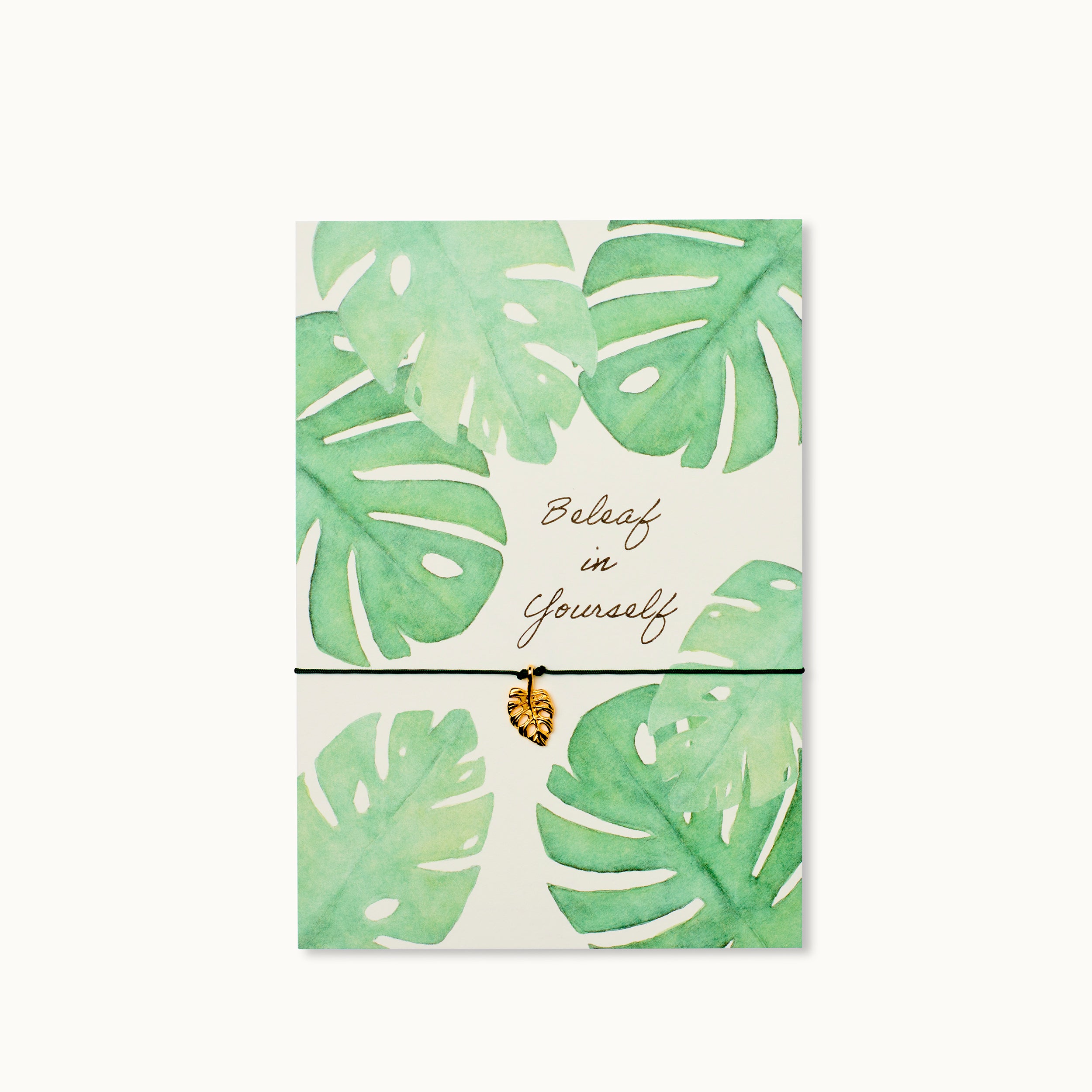 Karte mit einem Monstera Blatt als 18K vergoldeter Anhänger an einem dunkelgrünen Armband.