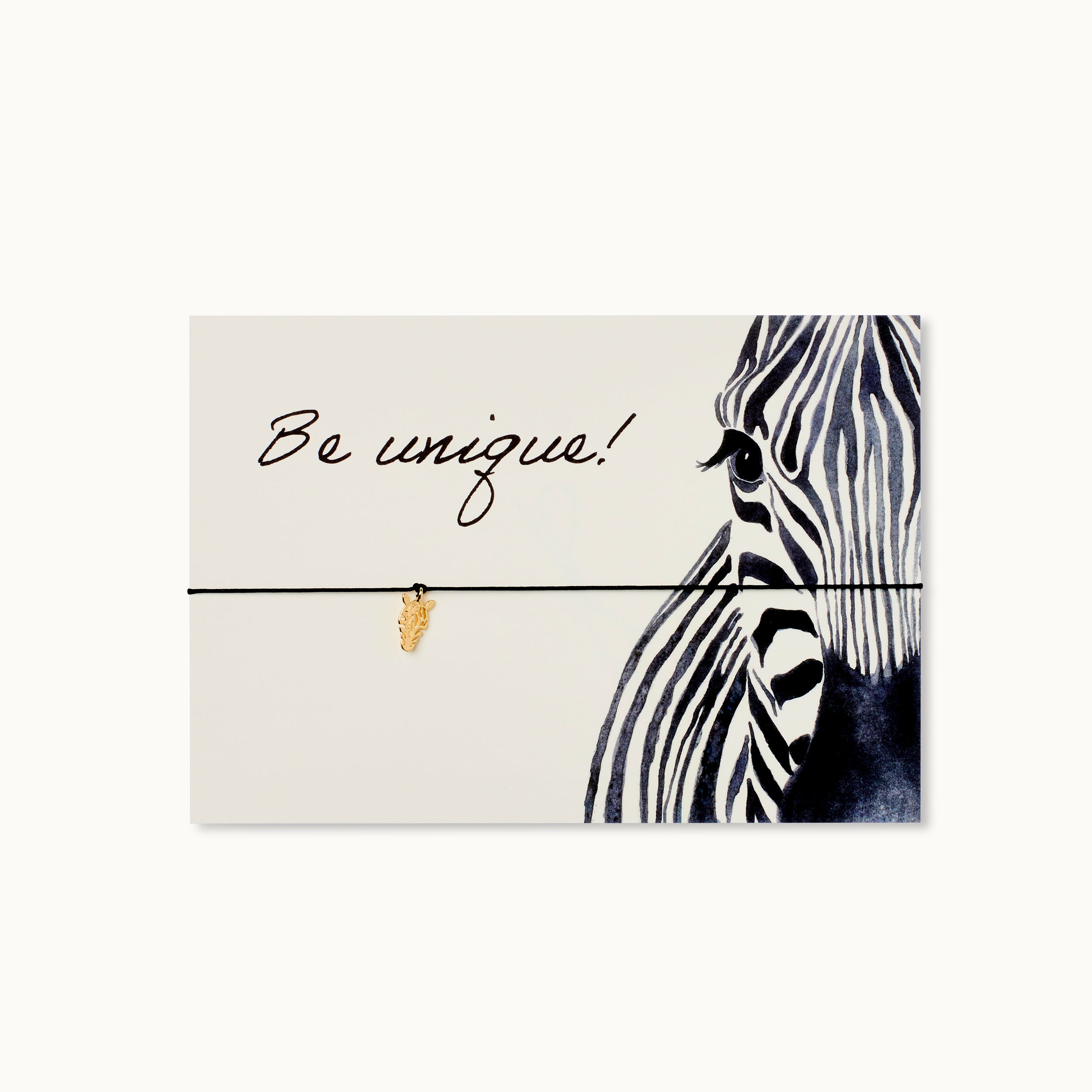 Be unique! Karte mit einem Zebra als 18K vergoldeter Anhänger an einem schwarzen Armband.